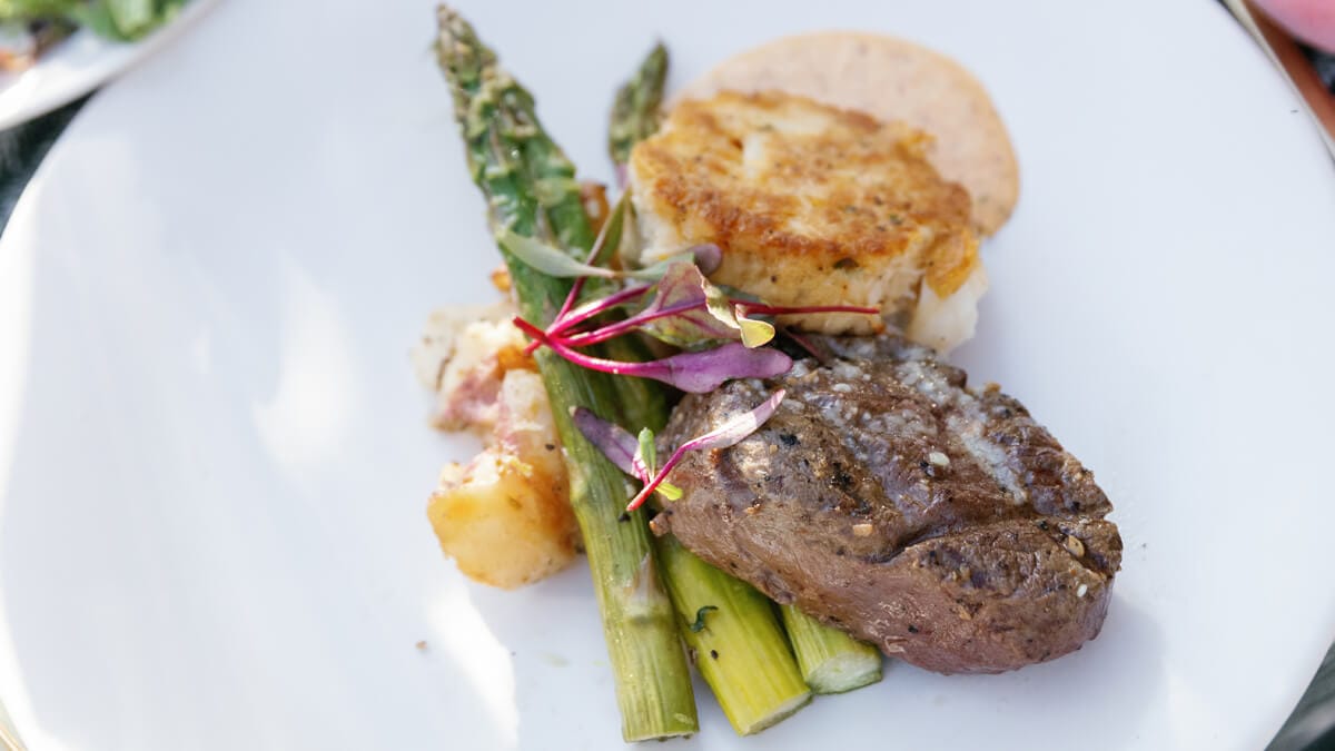 Close up of plate with steak, asparagus, and crabcake.