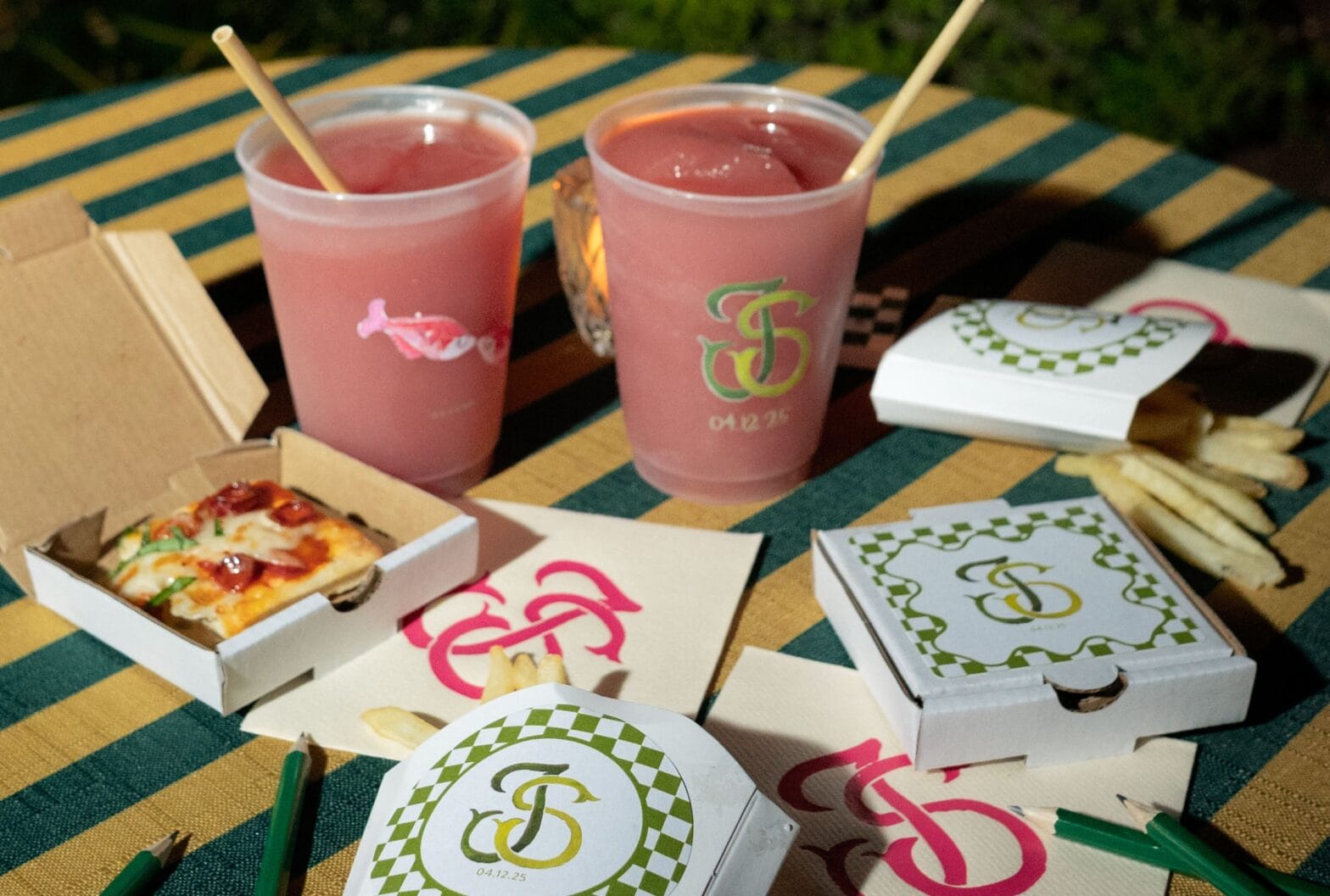 Tiny pizza boxes on table with pink frozen drinks.